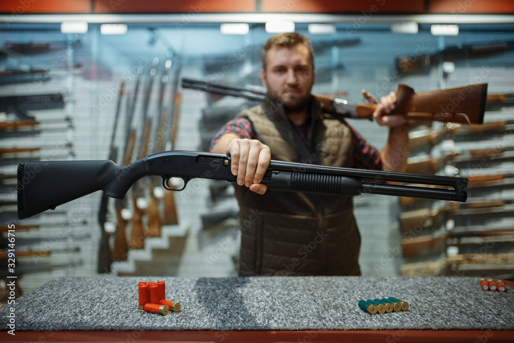 A shop owner behind the counter with a rifle